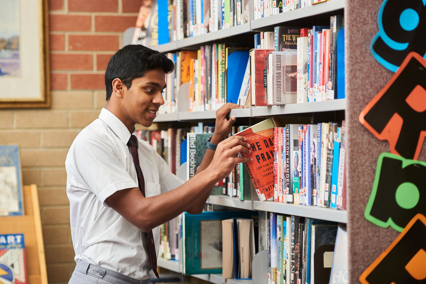 Boy taking a book off a library shelf